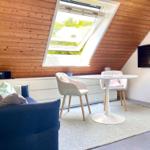 Wohnzimmer mit Dachfenster, Sofa, Esstisch und Fernseher an der Wand.