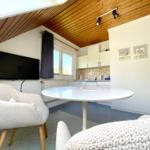 Wohn- und Küchenbereich mit runder Tisch, Fernseher und Holzdecke.