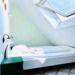 Schlafzimmer mit Dachschrägen, Fenster und Bett mit weißer Bettwäsche.