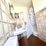 Badezimmer mit Dusche, Waschbecken und Toilette. Fliesen an Wänden und Boden.