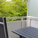 Terrasse mit Tisch und Stühlen. Blick auf grüne Bäume.