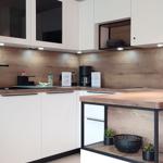 Moderne Küche mit Holzoberflächen und weißen Schränken. Arbeitsfläche mit integriertem Kühlschrank.
