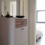 Schlafzimmer mit Bett und Fenster. Flur mit Schrank, Spiegel und Pflanze.