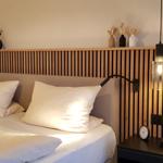Schlafzimmer mit Bett, Holzpaneelen und Nachttischen mit Lampen.