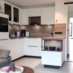 Wohnküche mit Sofa, Küchenzeile und Essbereich. Moderne Einrichtung mit Holz- und Metallakzenten.