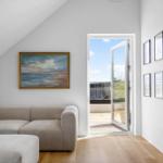 Wohnzimmer mit Sofa, Tür zum Balkon und Wandbildern.