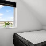 Schlafzimmer mit Dachschrägen, Bett und Fenster mit Pflanze.