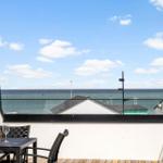 Terrasse mit Tisch und Stühlen, Blick auf Meer und Dänemarkflagge.