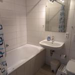 Badezimmer mit Badewanne, Spiegel, Waschbecken und Toilette.