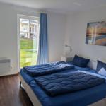 Schlafzimmer mit Doppelbett, Fenster zur Terrasse und Wandbild.