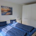 Zimmer mit Doppelbett, weißen Schränken und Wandbild mit Strandmotiv.