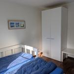 Schlafzimmer mit Bett, Kleiderschrank und Tisch. Wandbild mit Strandmotiven.