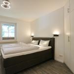 Schlafzimmer mit Bett, Fenster, Kleiderschrank und Wand-TV.