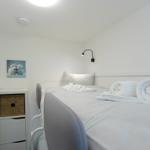 Ein Schlafzimmer mit Bett, Nachttisch und Wandbild. Handtuch und Kissen sind auf dem Bett.