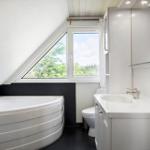 Badezimmer mit Dusche, Badewanne und Fenster. Dachgeschoss mit schräger Decke.