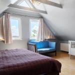 Schlafzimmer mit Dachfenster, Bett, Sofa und Kinderbett.