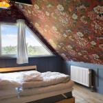 Schlafzimmer mit floraler Tapete, Holzbett und Dachfenster mit Blick auf Wald.