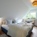 Schlafzimmer mit Dachschrägen, Bett, Fenster und Holzboden.