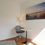 Eckzimmer mit Stuhl, Tisch und Wandbild von Strand