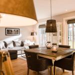 Esszimmer mit Holztisch und Stühlen, Wohnbereich mit Sofa und Fenster zur Außenterrasse.