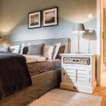 Schlafzimmer mit Bett, Nachttisch und Wandbildern. Durchgang zur Küche sichtbar.