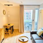 Wohnzimmer mit Sofa, Esstisch und Balkonzugang.