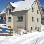 Ein zweistöckiges Haus mit Schneebedecktem Dach und Fenstern, umgeben von schneebedeckten Bäumen.