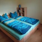 Ein Schlafzimmer mit einem Doppelbett, blau-weißem Bettzeug und einem Holzregal.