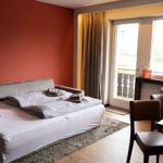 Schlafzimmer mit Bett, Tisch und Stühlen. Fenster mit Blick auf Balkon und Nachbarhaus.