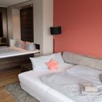 Schlafzimmer mit Doppelbett, rosa Wand und Spiegel. Handtuch auf Bett.