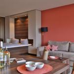 Wohnbereich mit Sofa, Tisch und Essbereich. Rote Wand, Spiegel und Bett im Hintergrund.