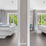 Zwei Schlafzimmer mit Blick auf grüne Außenbereiche und Fenstern mit Vorhängen.