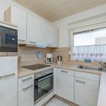 Küche mit weißen Schränken, Edelstahlspüle und Fenster mit Vorhang.