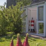 Garten mit Blick auf eine Glasveranda mit rotem Leuchtturmmodell.