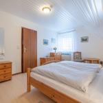 Schlafzimmer mit Holzbett, Kleiderschrank und Sitzgelegenheit unter Dachschrägen.