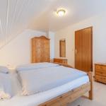 Schlafzimmer mit Doppelbett, Holzmöbel und schrägem Dach