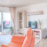 Wohnzimmer mit orangefarbenen Sesseln, Kaminofen und Glasfront zur Terrasse.