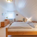Schlafzimmer mit Holzbett, Schrank und Tisch. Dachboden mit weißer Holzdecke.