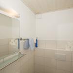 Badezimmer mit Spiegel, Handtuchhalter und Toilettenpapier.