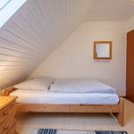 Schlafzimmer mit Holzbett, Nachttisch und Spiegel an der Wand