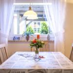 Esstisch mit Stühlen, Blumen und Fenster mit Vorhängen.
