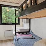Schlafzimmer mit Doppelstockbett, Schreibtisch und Fenster zum Wald.