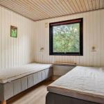 Zwei Betten in einem Raum mit Holzdecke und Fenster zum Wald.