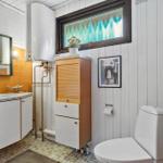 Badezimmer mit Waschbecken, Spiegel, Toilette und Holzschränken.