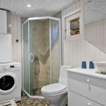 Badezimmer mit Dusche, Toilette, Waschmaschine und Waschtisch mit Schale.