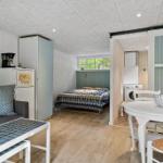 Wohnraum mit Schlafzimmer, Esstisch und Waschmaschine. Holzfußboden und weiße Möbel.