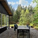 Terrasse mit Tisch und Stühlen neben einem Haus im Wald.