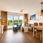 Wohn- und Essbereich mit Holzboden, Sofa, TV und Balkon.