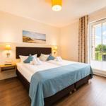 Schlafzimmer mit Doppelbett, Schlafcouch und Balkonansicht.