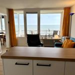 Living room with sea view, sofa, armchair, and kitchen island.